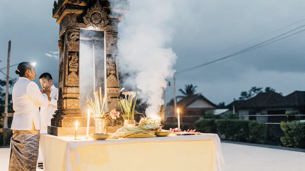 Canang sari ziedu upuru grozi pie akmens tempļa rītausmā ar vīraka dūmiem Canang sari ziedu upuru grozi pie akmens tempļa rītausmā ar vīraka dūmiem